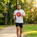 Man running in a park wearing a white t-shirt with a red logo