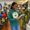 Young girl in a green hoodie holding a book in a bookstore.